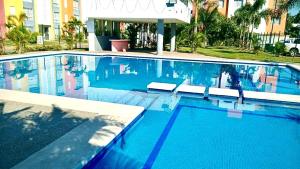 a swimming pool with blue water in front of a building at Acapulco Vibes - Departamento con Alberca Cerca de Punta Diamante in Acapulco