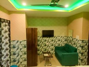 a living room with a green couch and a tv at Top Comfort in Kolkata