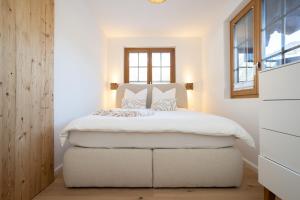 a bedroom with a large white bed with a window at Chalet Valentina in Chateau-d'Oex
