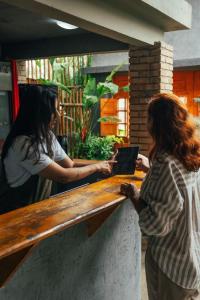 Zwei Frauen stehen mit einem Laptop an einem Tresen. in der Unterkunft Jimbaran Pousada & Bistrot in Maragogi