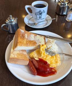 a plate with eggs sausage and toast and a cup of coffee at SUITE De PARIS in Abuja