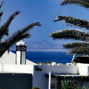a view of the ocean from a house with palm trees at Studio Paraíso - Casa Paraíso Playa Blanca in Playa Blanca