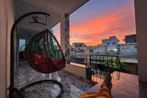 a person laying on a balcony watching the sunset at Chitrangan The Homestay of Udaipur in Udaipur