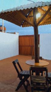 a table and a chair under an umbrella at BELL MAR CHALÉs 03 in Luis Correia