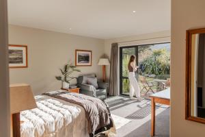 a woman in a hotel room with a bed and a window at Manakau Lodge in Kaikoura