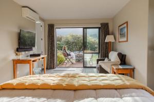 a bedroom with a bed and a living room with a balcony at Manakau Lodge in Kaikoura