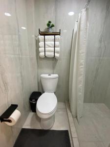 a bathroom with a toilet and a shower and towels at Oasis Hotel Jojutla in Vallespin