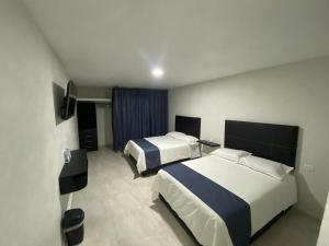 a hotel room with two beds and a television at Oasis Hotel Jojutla in Vallespin