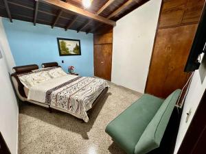 a bedroom with a bed and a green chair at Hostel Urban City Medellin in Medellín