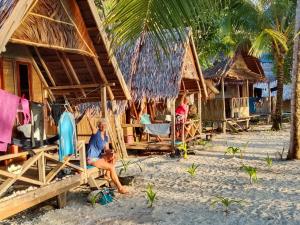a group of people sitting in chairs in front of a resort at Or Mandira Homestay in Pulau Penemu