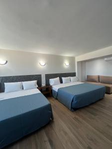 ein Hotelzimmer mit zwei Betten und einer Couch in der Unterkunft Hotel Universo in Guadalajara