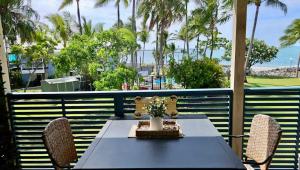 a table and chairs on a balcony with palm trees at La Plage Cabane in Eimeo