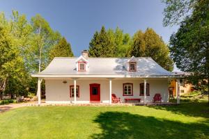 a white house with a red door and a yard at Maison Bilodeau Ethier - 5 chambres - 13 personnes in Saint-Férréol-les-Neiges