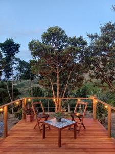 a wooden deck with two chairs and a table at Chalé inteiro Canto da Graúna in Ibicoara