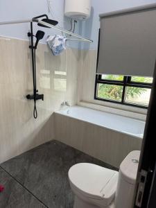 a bathroom with a toilet and a tub and a window at d'house toraja in Rantepao