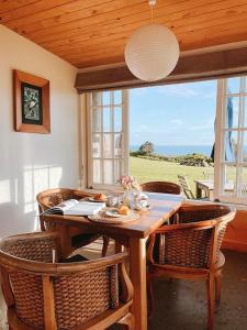 a dining room with a table and chairs and a window at Ahu Ahu Beach Villas in Oakura