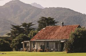 a house in a field with mountains in the background at Ahu Ahu Beach Villas in Oakura