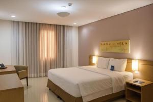 a hotel room with a large bed and a desk at Flat Premium Manaus no Adrianópolis in Manaus