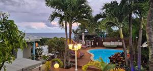 a resort with a swimming pool and palm trees at Les Gîtes Blue Karaib in Sainte-Anne