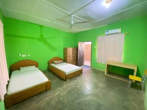 a room with two beds and a green wall at Savannah Lodge in Larabanga