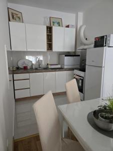 a kitchen with white cabinets and a table and chairs at Central Lux in Čačak