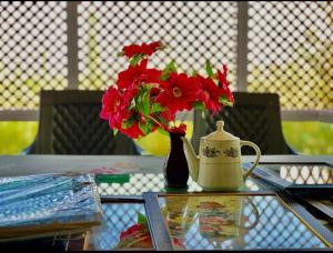 a vase with red flowers and a tea kettle on a table at D’SHIEKHS RESORT GUREZ in Kanzalwan +22 photos