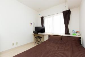 a bedroom with a bed and a desk and a window at アセット北初富 - 長期滞在歓迎 キッチン付きで一人旅やビジネス出張におすすめ 成田空港へ直通 in Kamagaya