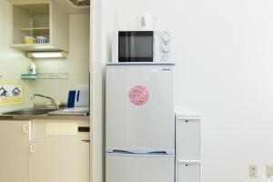 a refrigerator with a microwave on top of it in a kitchen at アセット北初富 - 長期滞在歓迎 キッチン付きで一人旅やビジネス出張におすすめ 成田空港へ直通 in Kamagaya