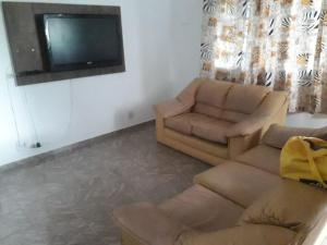 a living room with a couch and a tv at casa de praia grande e espaçosa in Bertioga