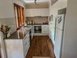 a kitchen with white cabinets and a white refrigerator at The Unit Lennox Head in Lennox Head