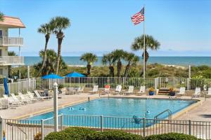 a swimming pool with an american flag and the ocean at Spanish Trace 235 in St. Augustine