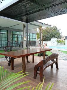 a wooden picnic table and benches under an umbrella at Loft Life Pool villa in Ban Huai Yai