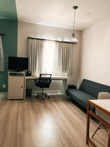 a living room with a couch and a desk with a computer at Flat Hotel Confort Suítes Alphaville in Barueri +1 photo