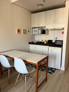a kitchen with a table and two white chairs at Flat Hotel Confort Suítes Alphaville in Barueri