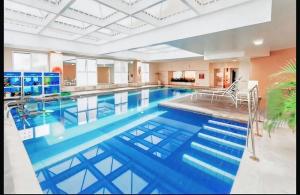a large pool with blue water in a building at Flat Hotel Confort Suítes Alphaville in Barueri