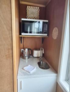 a small kitchen with a sink and a microwave at Tide and Tranquility - Guest Studio in Snells Beach