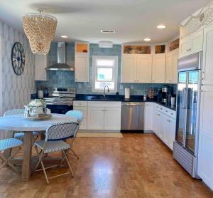 a kitchen with white cabinets and a table with chairs at Nautical Endeavors Beach House Steps from Surf in Rodanthe