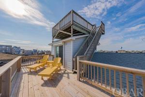 a deck with chairs and a building with a balcony at Nautical Endeavors Beach House Steps from Surf in Rodanthe