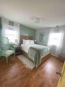 a bedroom with a bed and a chair and windows at Nautical Endeavors Beach House Steps from Surf in Rodanthe