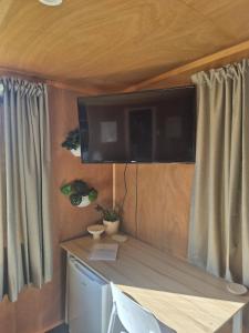 a room with a table and a tv on the wall at Tide and Tranquility - Guest Studio in Snells Beach