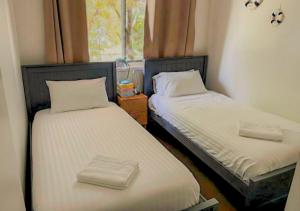 two twin beds in a room with a window at The Unit Lennox Head in Lennox Head