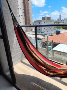 a hammock on a balcony with a view of a city at Lindo Studio com rooftop e piscina in Cabedelo