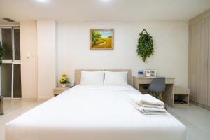 a white bedroom with a large bed and a desk at Jade House Tran Cao Van in Ho Chi Minh City