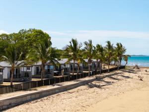a row of houses on a beach with palm trees at Tasman Holiday Parks - Rollingstone in Rollingstone
