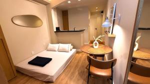 a small room with a bed and a table at Studio Quarto e Sala Moderno em Ipanema, próximo a praia in Rio de Janeiro +24 photos