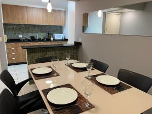 a dining room table and chairs with plates and glasses at Apto 33 - Completo no Centro de Foz in Foz do Iguaçu