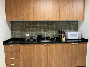 a kitchen with wooden cabinets and a sink and a microwave at Apto 33 - Completo no Centro de Foz in Foz do Iguaçu