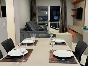 a dining room with a table with plates and glasses at Apto 33 - Completo no Centro de Foz in Foz do Iguaçu