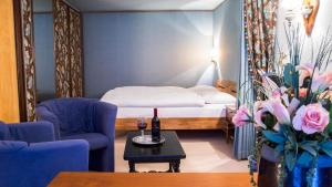 ein kleines Zimmer mit einem Bett und einem Tisch mit einer Flasche Wein in der Unterkunft Hotel Astoria in Leukerbad
