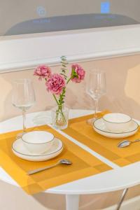 a table with two plates and two glasses and flowers at Aimee House Vũ Miên in Hanoi